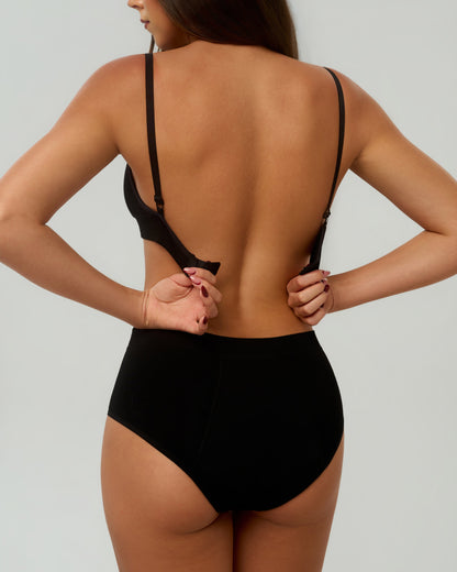 Model in Rudie black Leakproof High-Waist Brief putting bra on — rear view, seamless fit